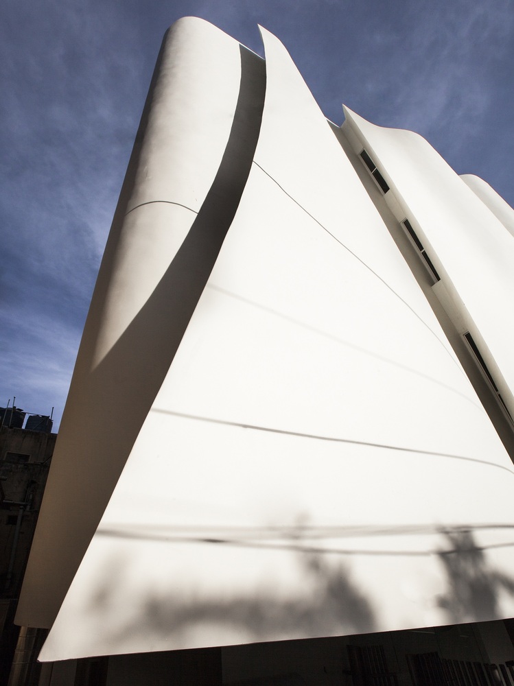 Cadence folds KMYF Health Clinic white facade with masonry techniques adjacent to Indian Temple