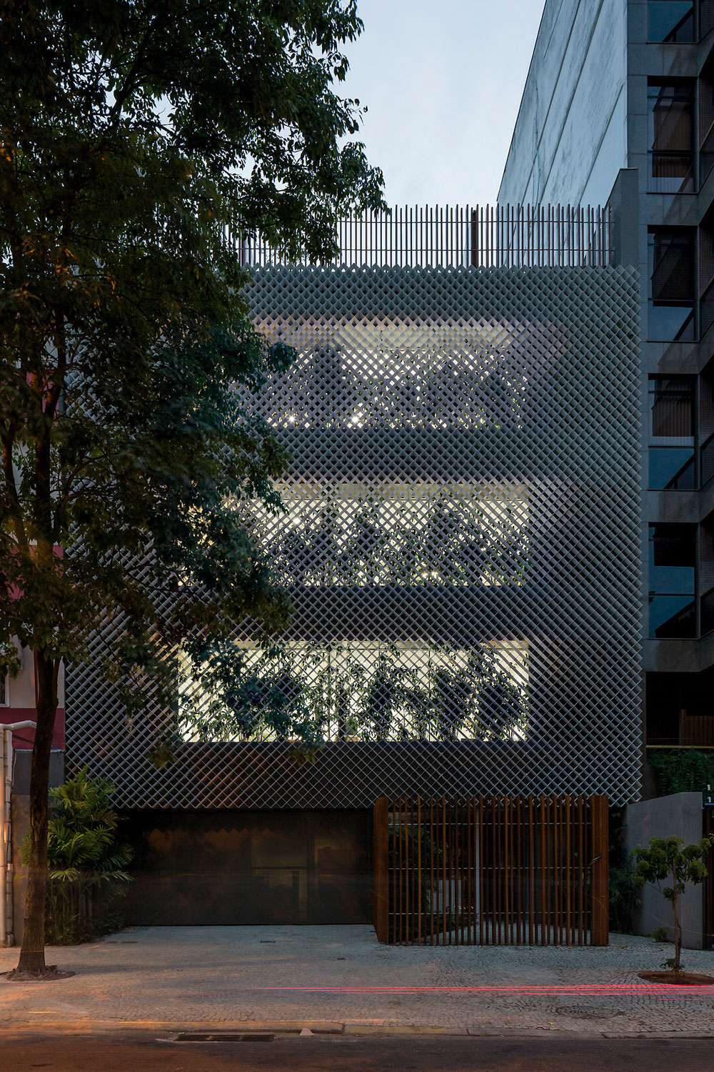 Anibal Office Building is wrapped by perforated aluminum filtering light and sound