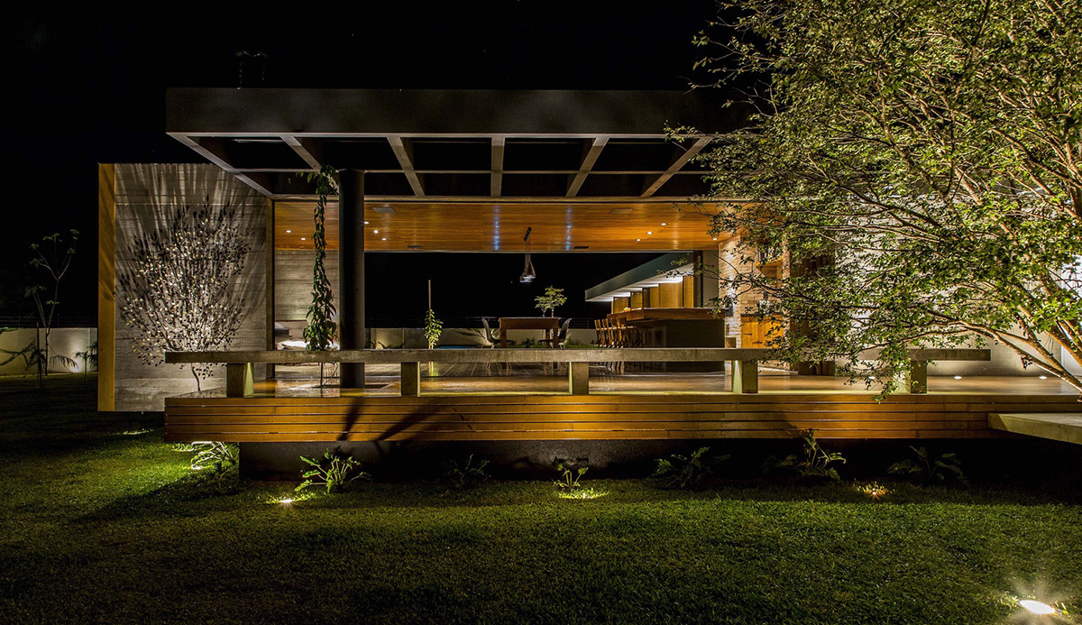 An elongated Brazilian house by Mf+Arquitetos is closed down by foldable  wooden shutters