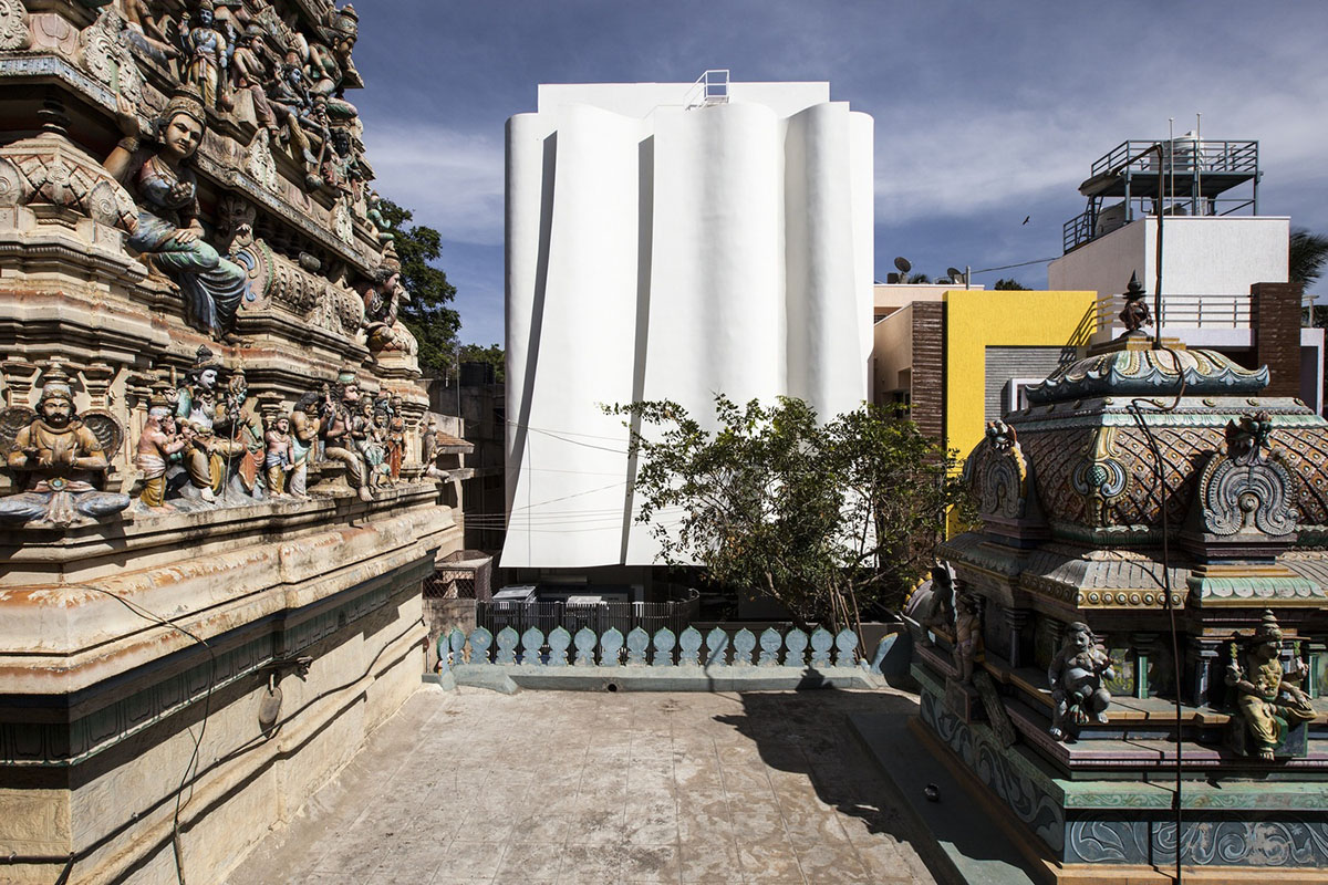 Cadence folds KMYF Health Clinic white facade with masonry techniques adjacent to Indian Temple