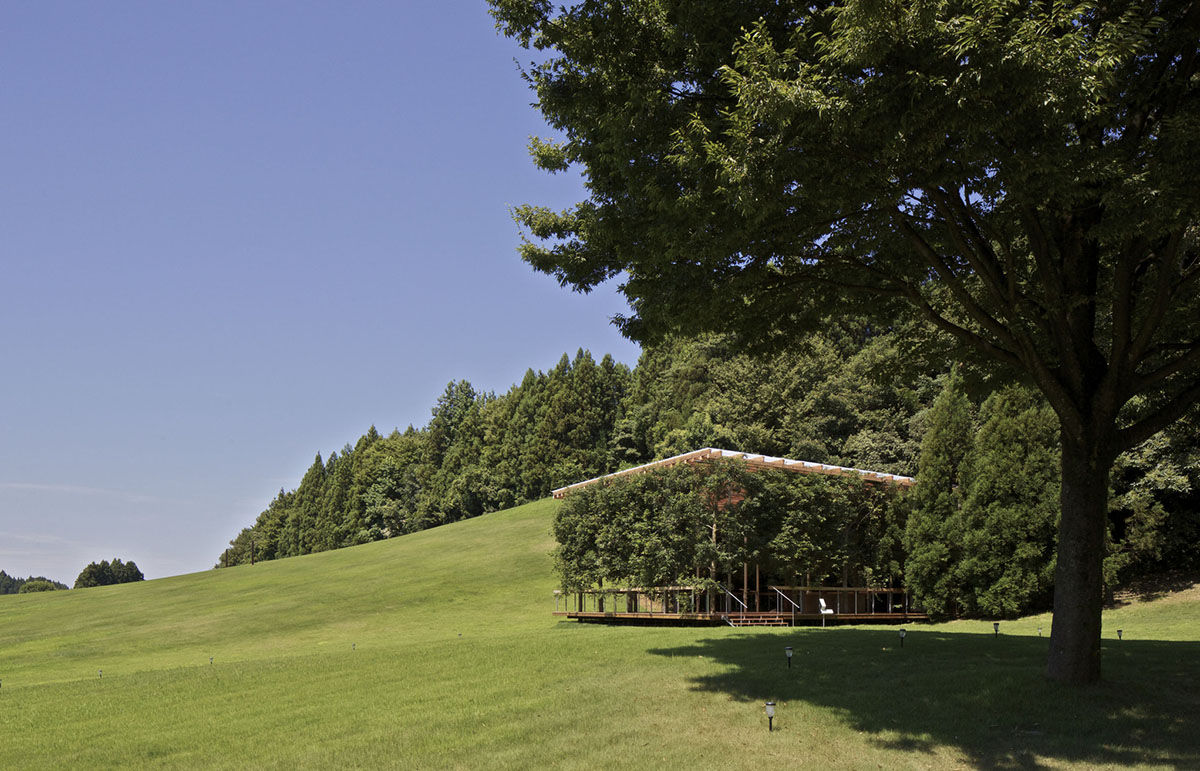 A multi-purpose venue is wrapped by living trees as an addition to open-air theatre in Japan