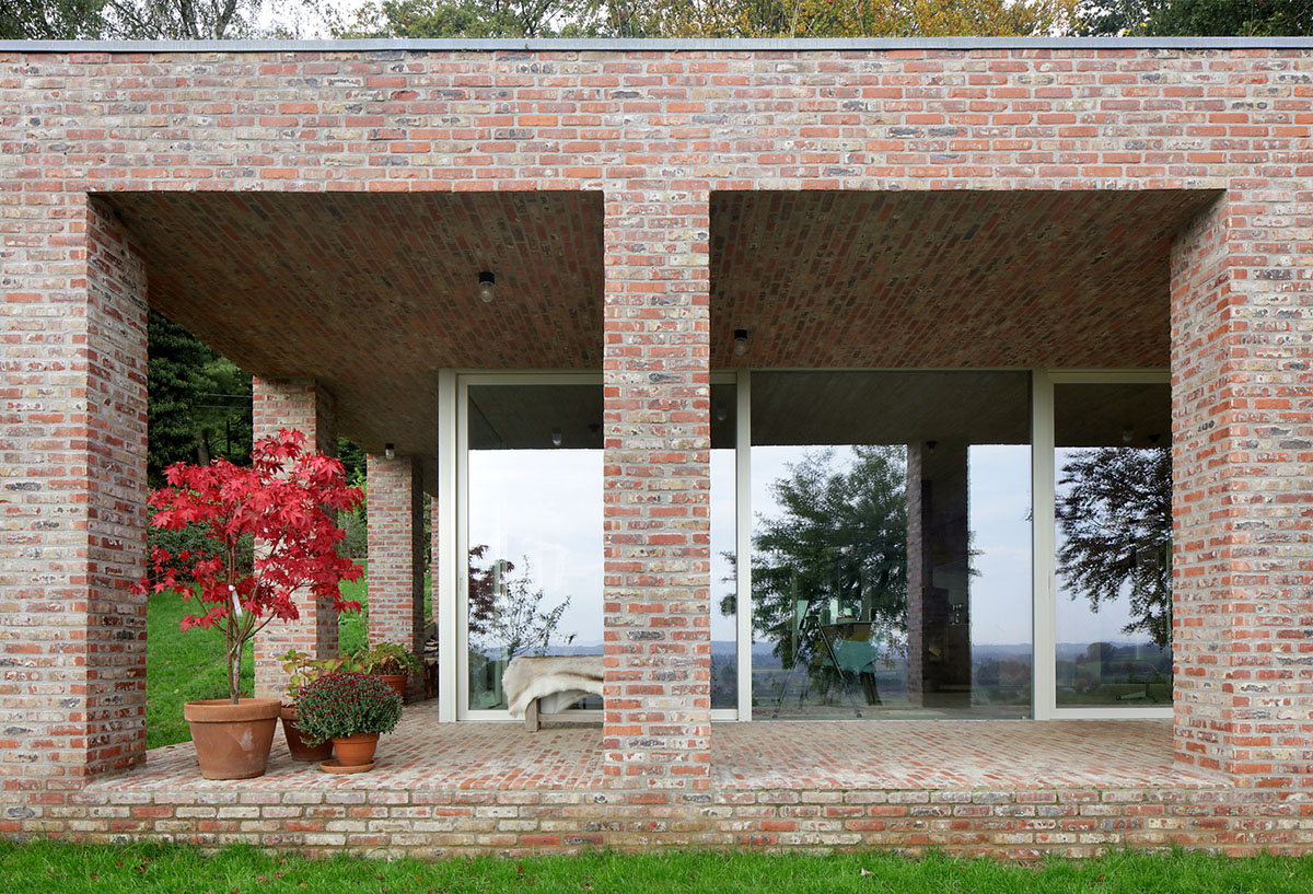 Studio Okami Architects built brick private villa embedded in the slope to offer infinite views