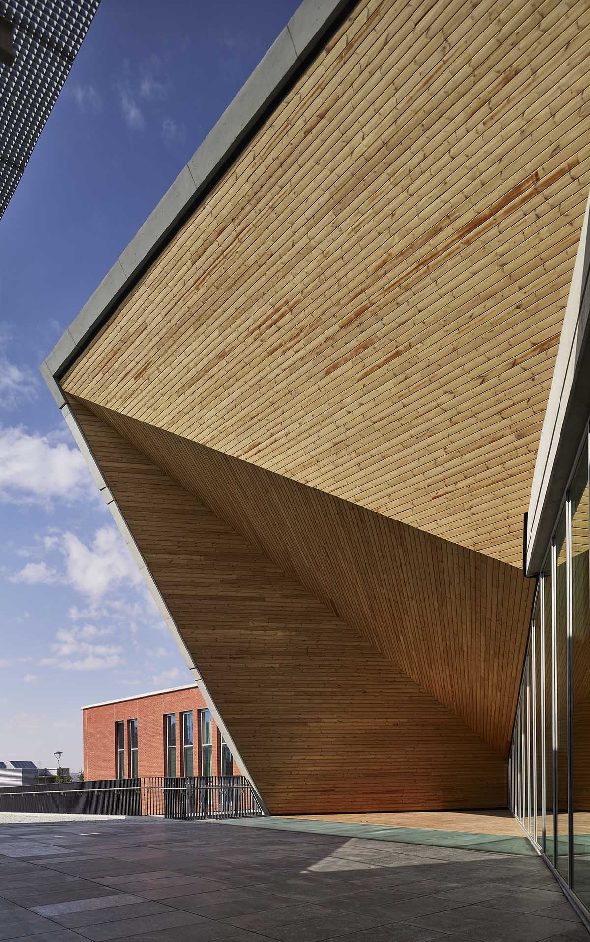 Uygur Architects articulates performing arts center façade with wooden triangulating surfaces