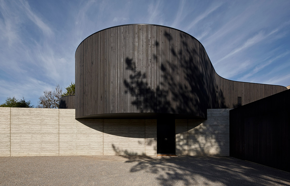 Wood Marsh built curvaceous home clad in dark timber contrasting its natural landscape in Portsea
