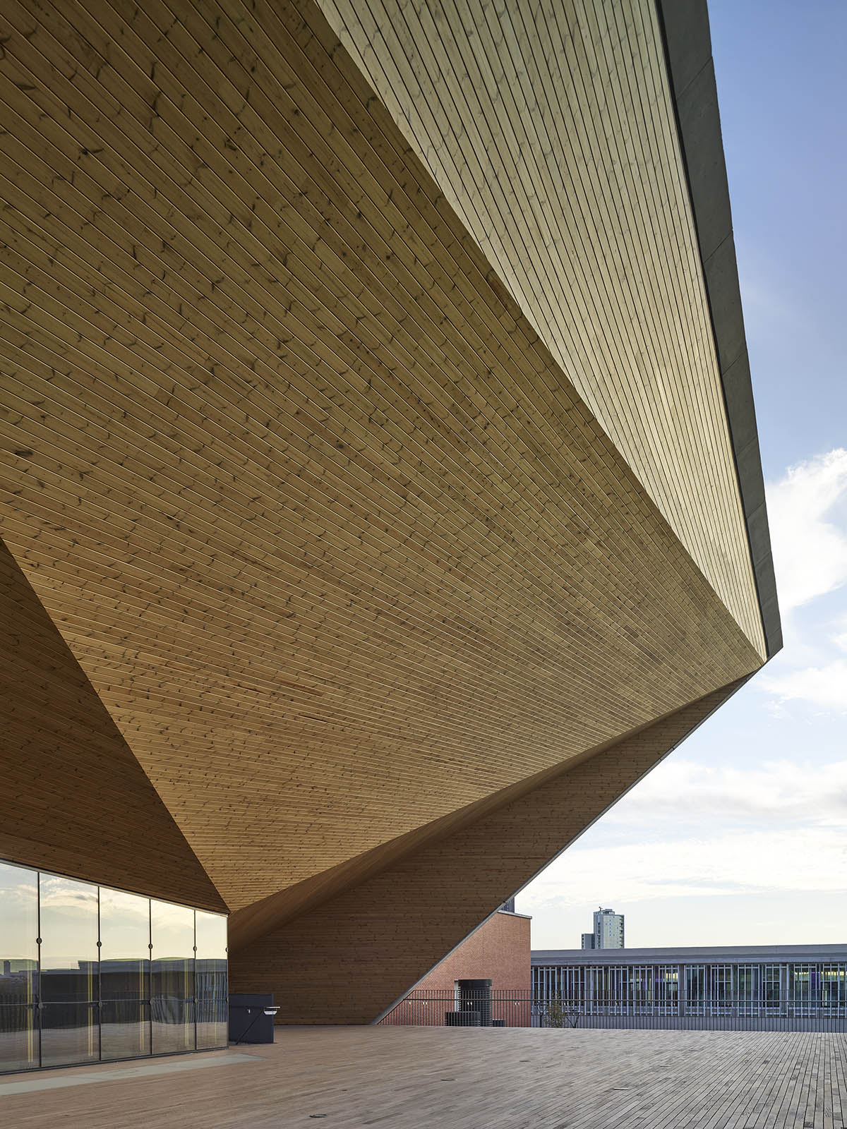 Uygur Architects articulates performing arts center façade with wooden triangulating surfaces