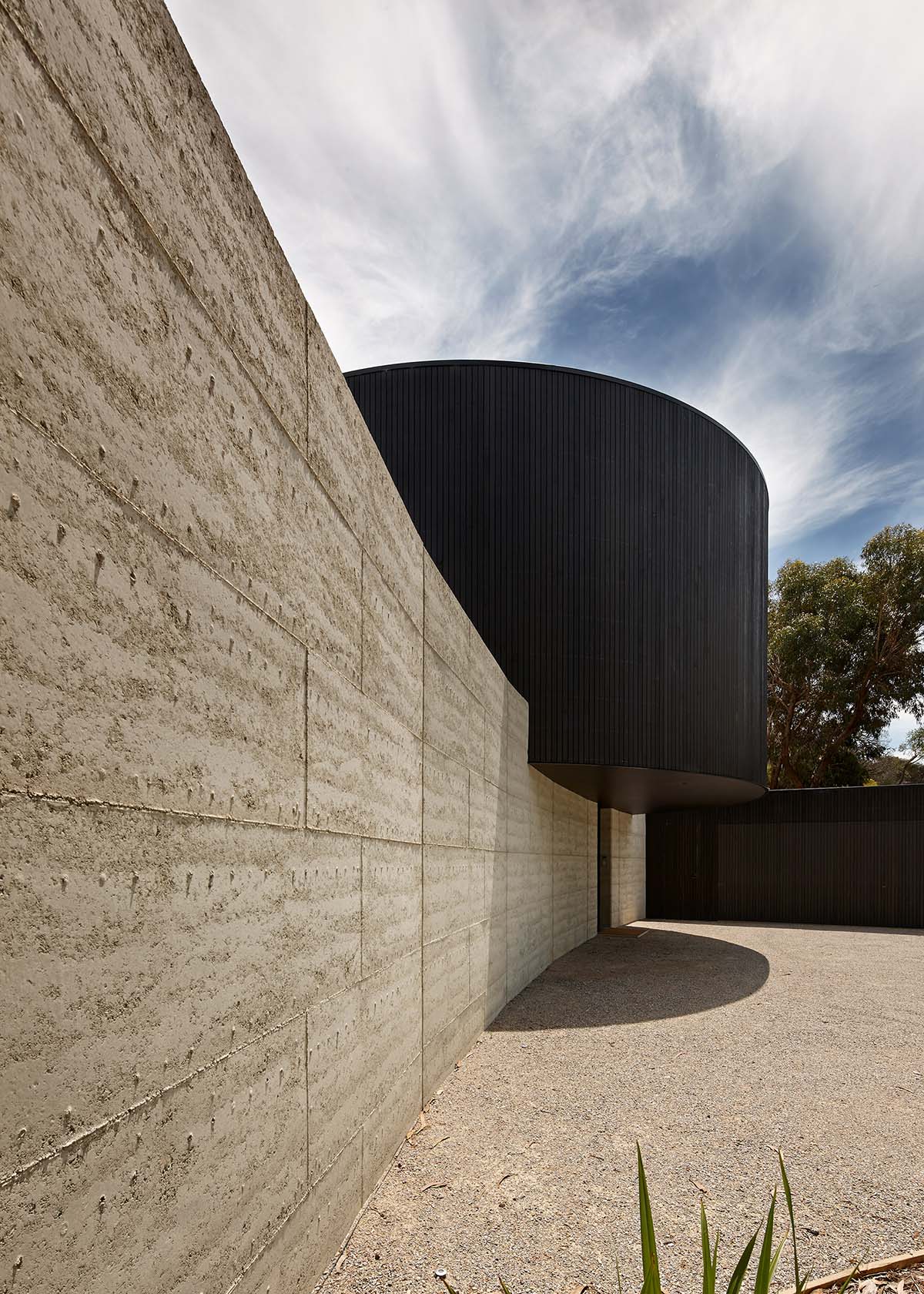 Wood Marsh built curvaceous home clad in dark timber contrasting its natural landscape in Portsea