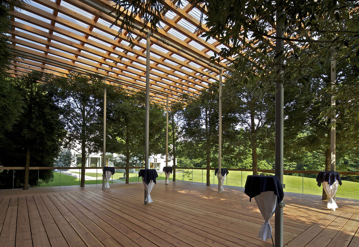 A multi-purpose venue is wrapped by living trees as an addition to open-air theatre in Japan