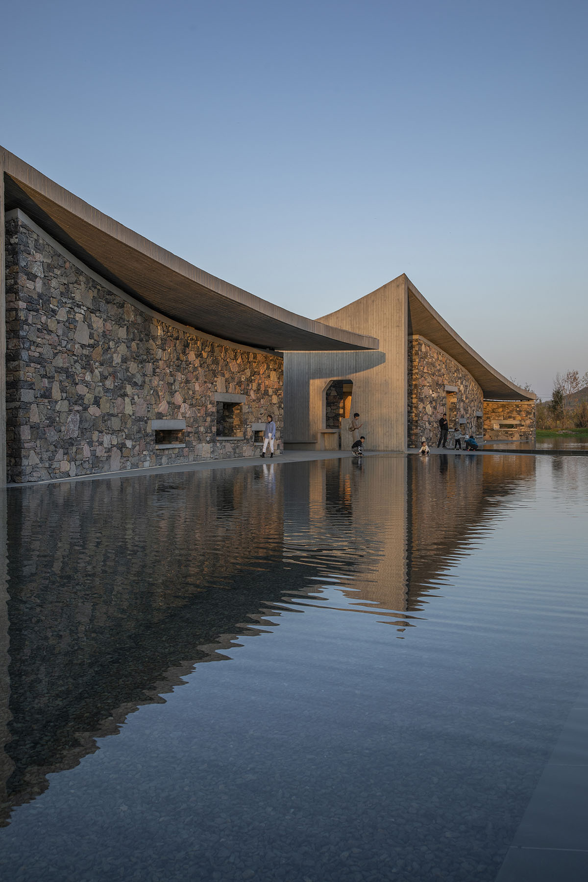 Concrete hyperboloid roofs cover masonry stone art center with a central courtyard in Shandong