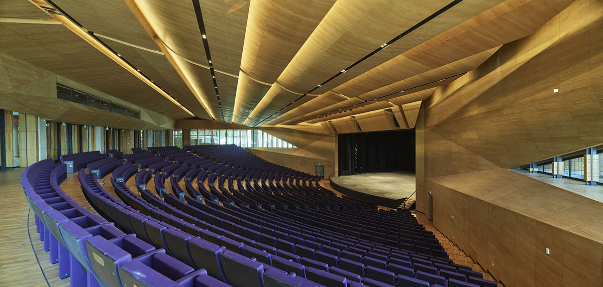 Uygur Architects articulates performing arts center façade with wooden triangulating surfaces