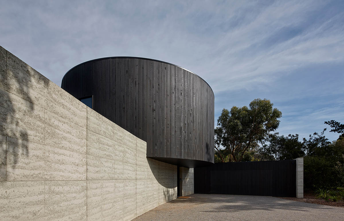 Wood Marsh built curvaceous home clad in dark timber contrasting its natural landscape in Portsea