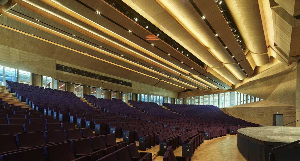Uygur Architects articulates performing arts center façade with wooden triangulating surfaces