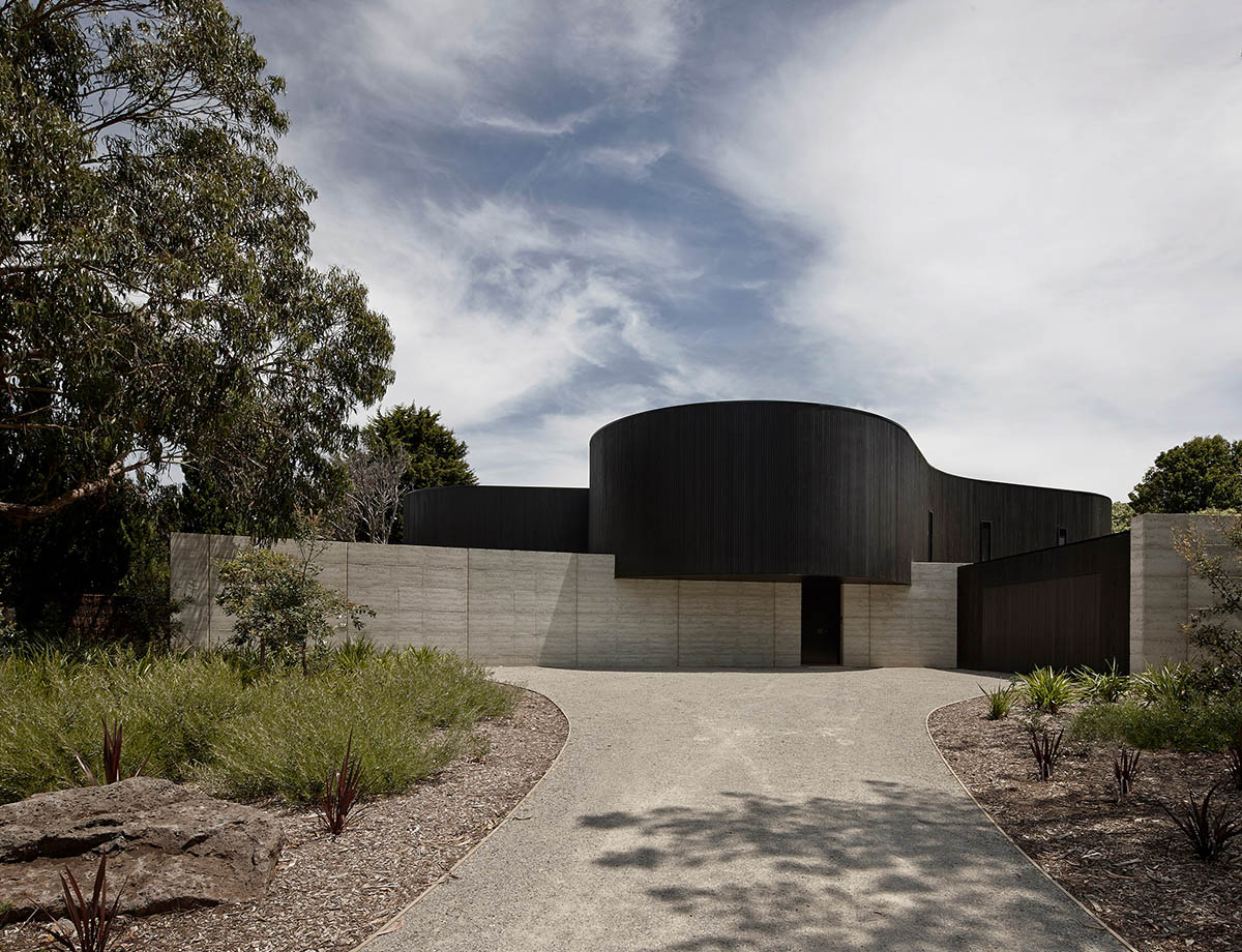 Wood Marsh built curvaceous home clad in dark timber contrasting its natural landscape in Portsea