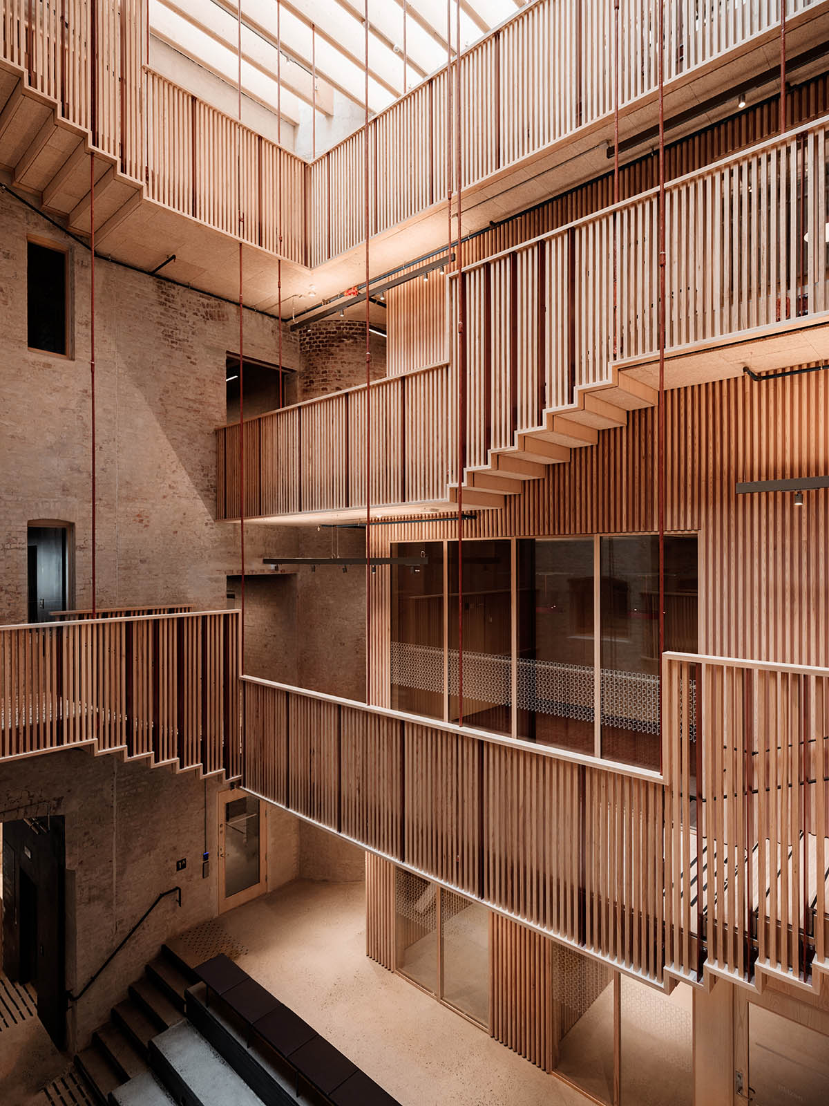 Atelier Oslo and KIMA Arkitektur restore former warehouse as a press house with light-lit atrium