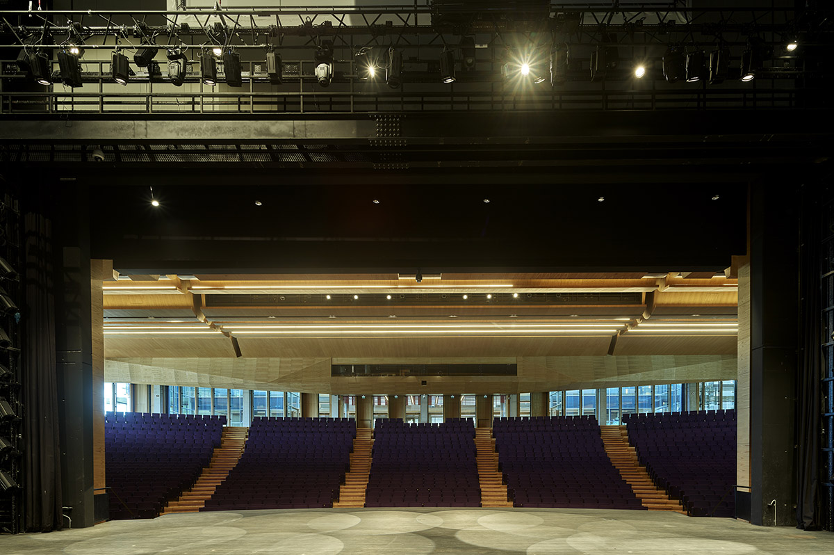 Uygur Architects articulates performing arts center façade with wooden triangulating surfaces