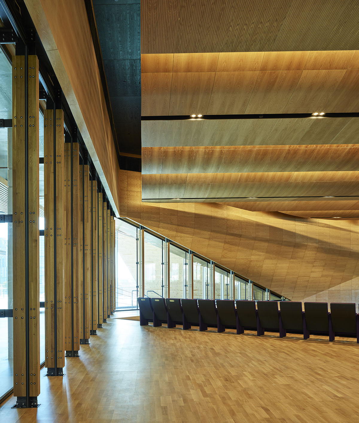Uygur Architects articulates performing arts center façade with wooden triangulating surfaces