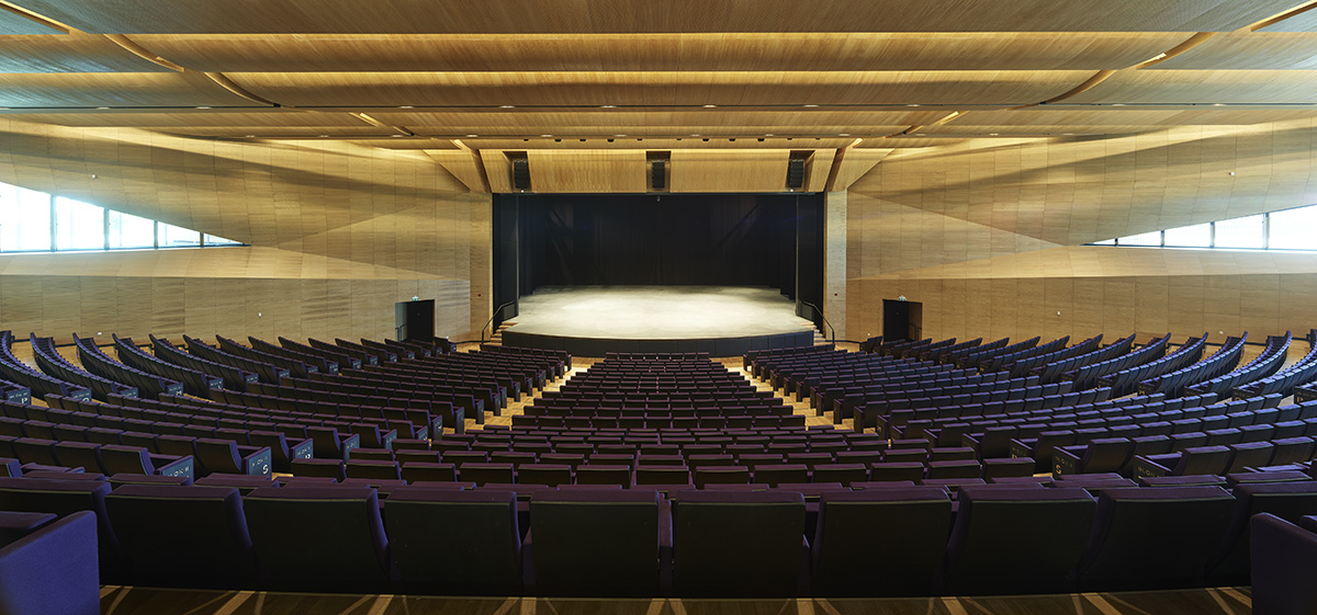 Uygur Architects articulates performing arts center façade with wooden triangulating surfaces