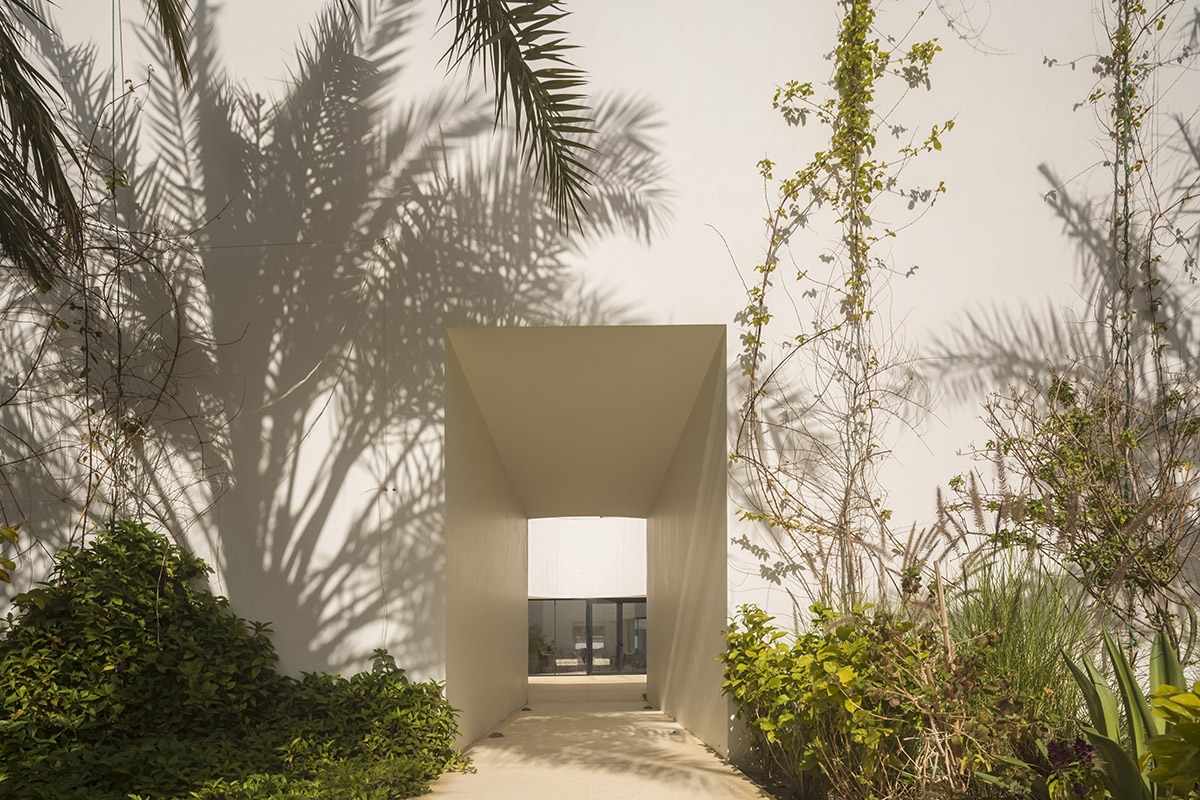 White Fortress by TAEP/AAP is a linear house that features a tall cylindrical lighthouse on a beach 