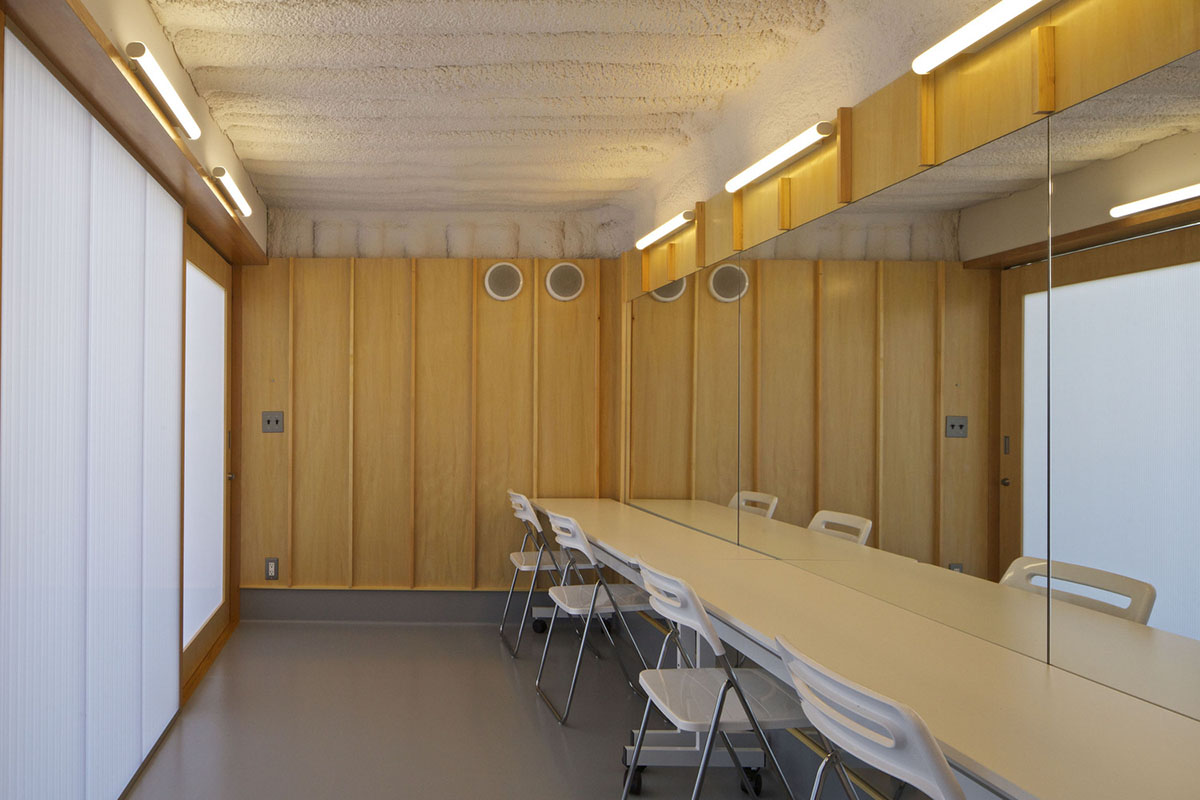 A multi-purpose venue is wrapped by living trees as an addition to open-air theatre in Japan