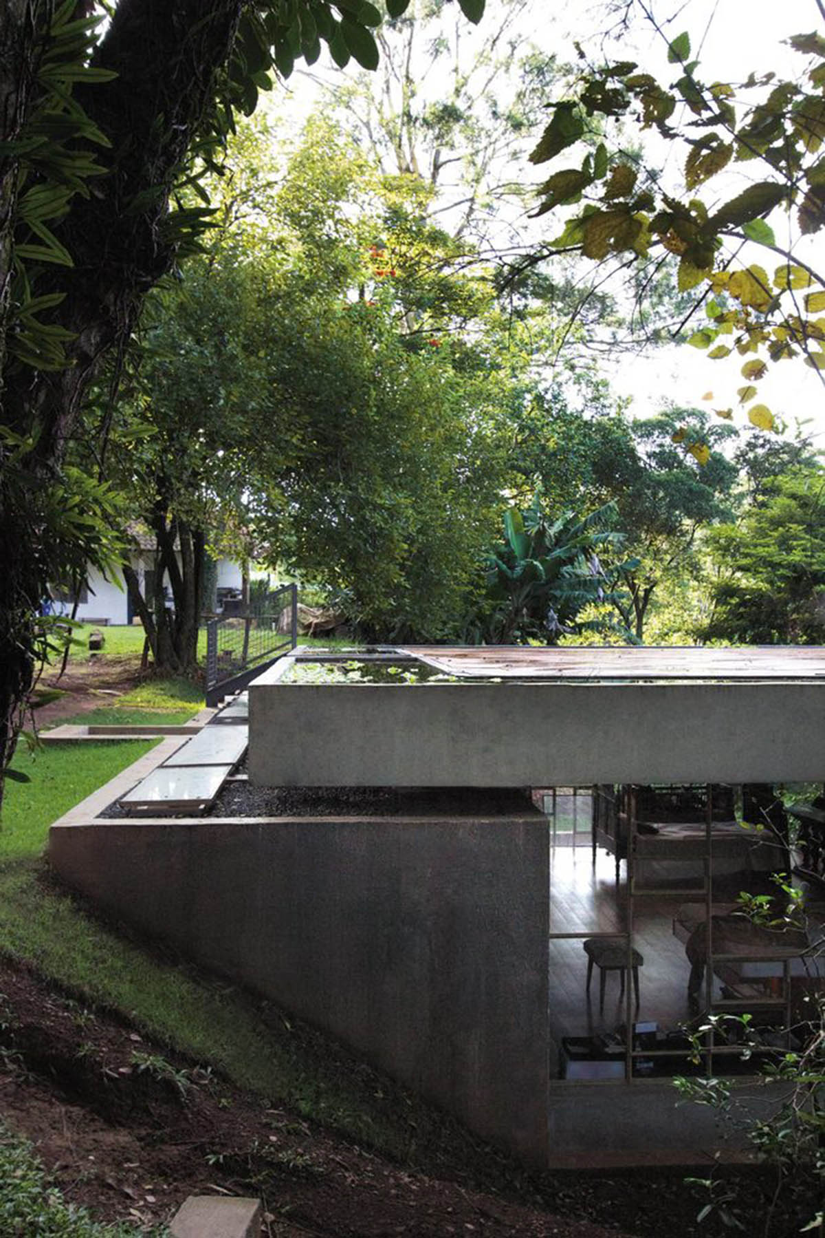Two bold concrete platforms define this transparent library house by Atelier Branco Arquitetura