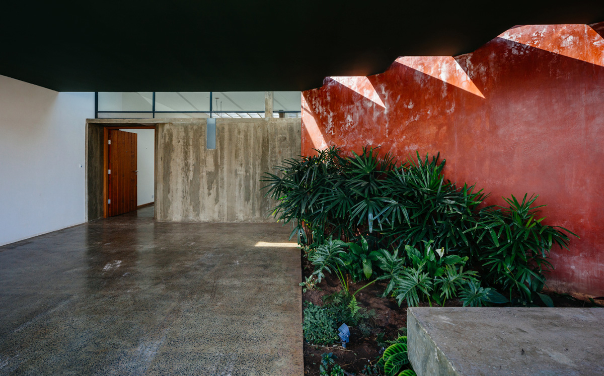 V&atilde;o designed recessed volumes and leaning red wall to offer flexible spaces for this Brazilian house