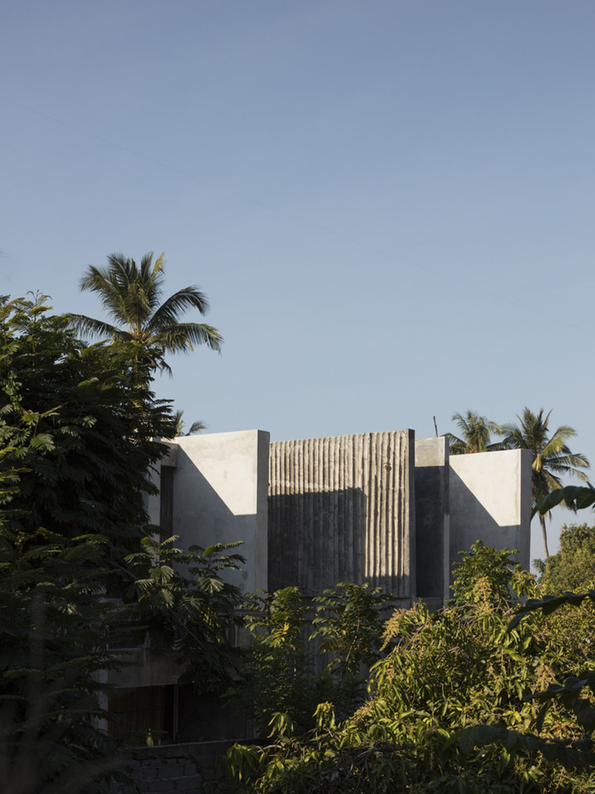 Linear concrete walls hide hotel rooms overlooking lush forest on the northern coast of Bali