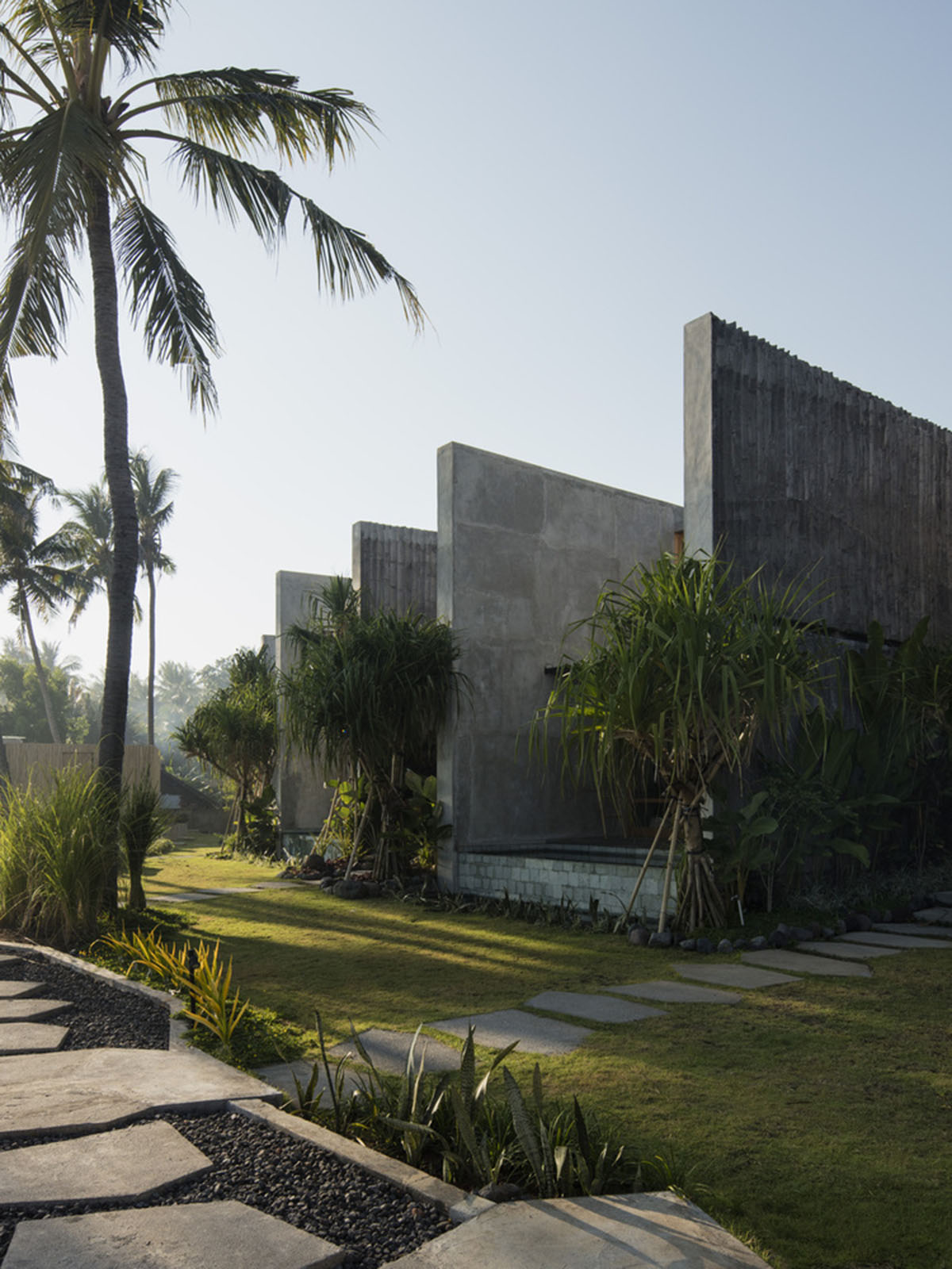 Linear concrete walls hide hotel rooms overlooking lush forest on the northern coast of Bali