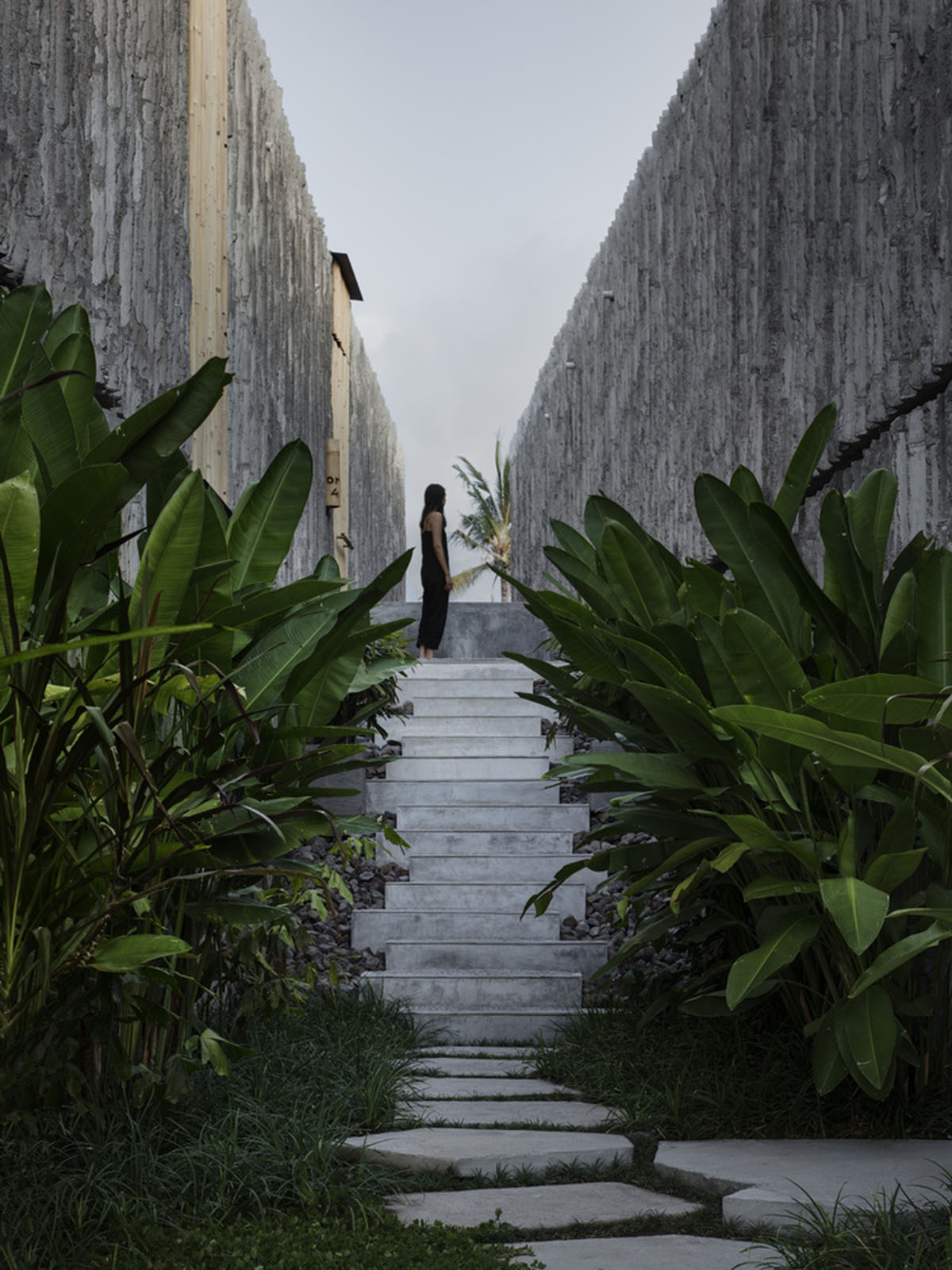 Linear concrete walls hide hotel rooms overlooking lush forest on the northern coast of Bali