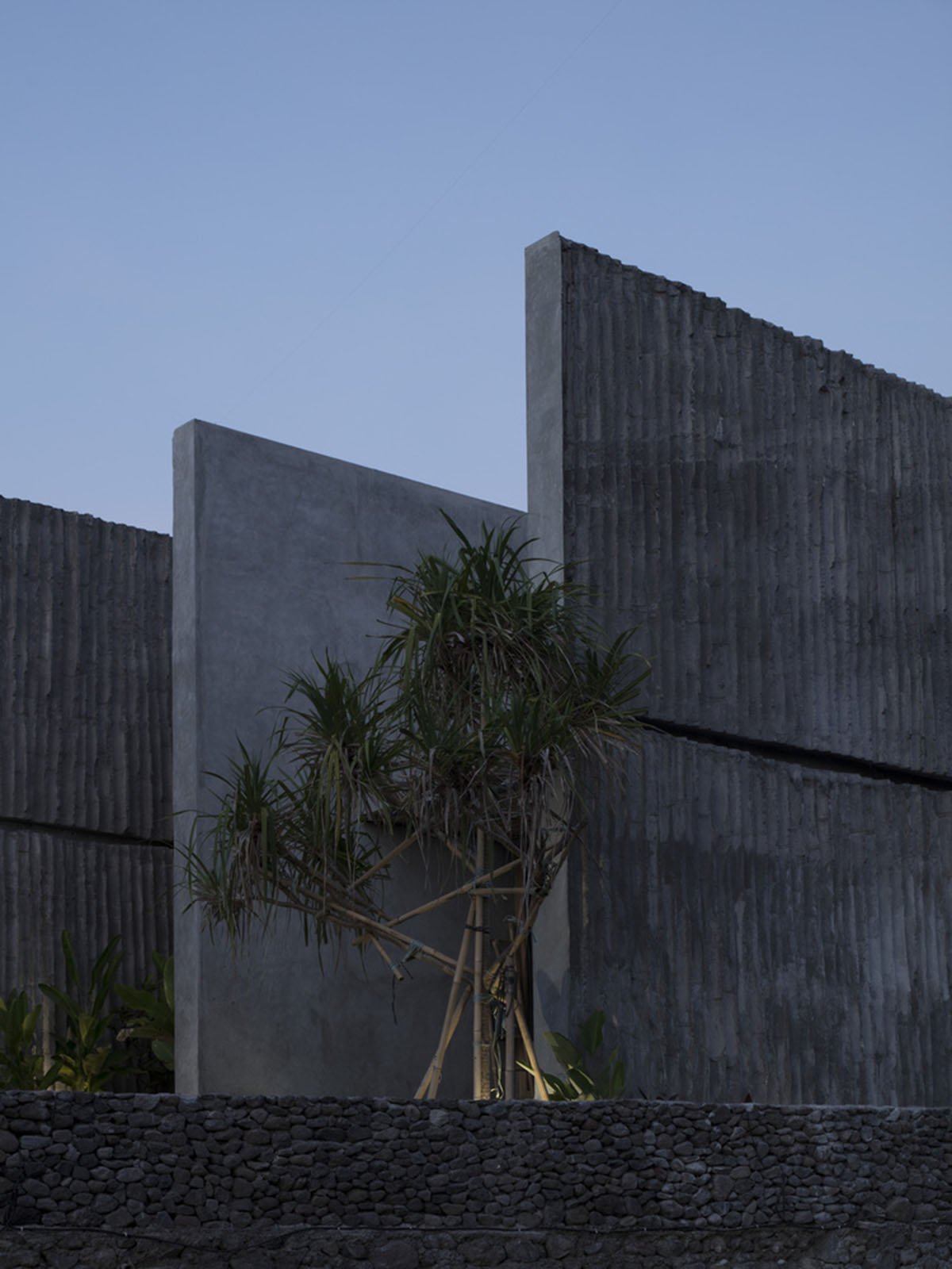 Linear concrete walls hide hotel rooms overlooking lush forest on the northern coast of Bali