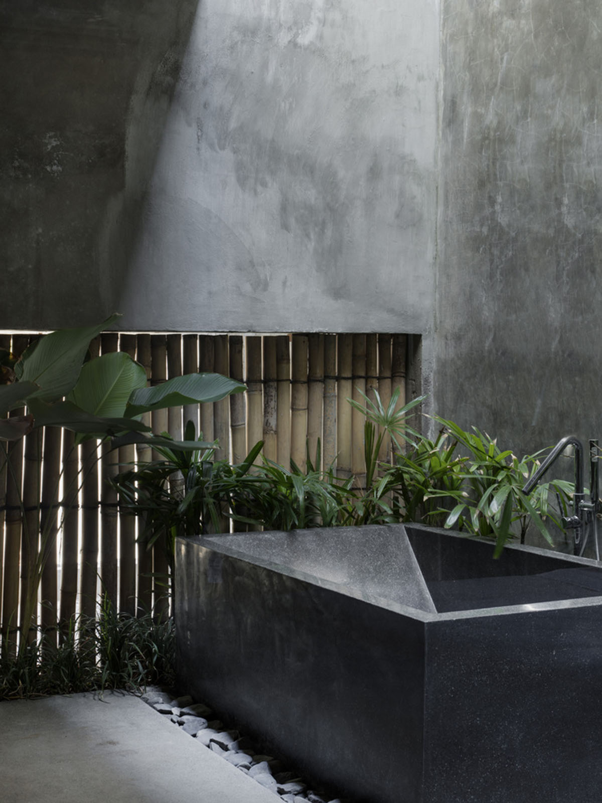 Linear concrete walls hide hotel rooms overlooking lush forest on the northern coast of Bali