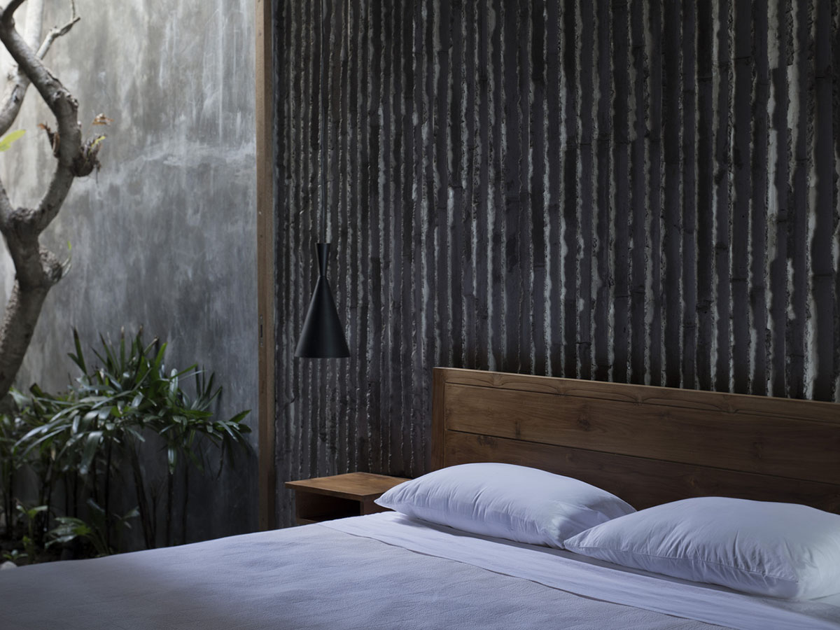 Linear concrete walls hide hotel rooms overlooking lush forest on the northern coast of Bali