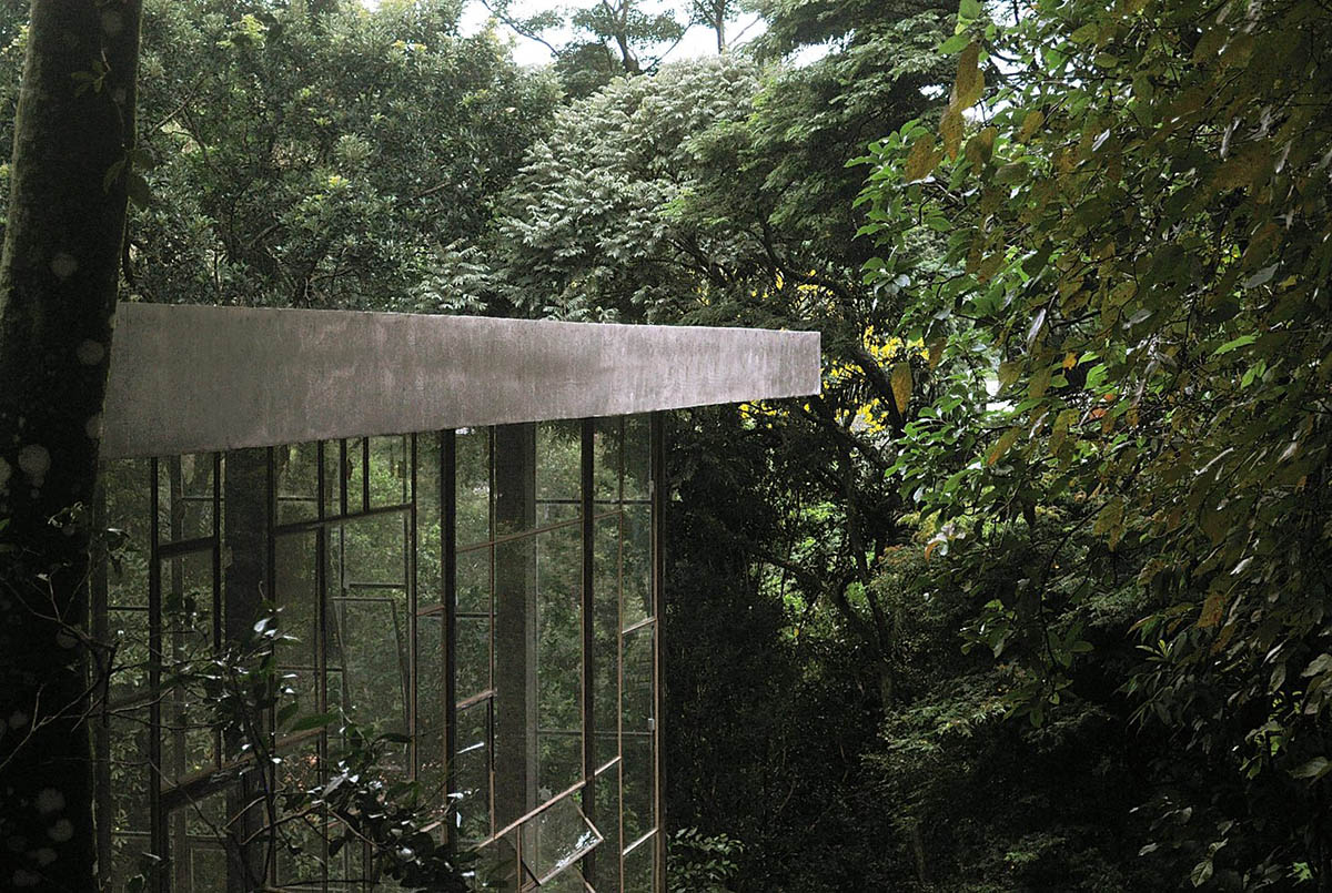 Two bold concrete platforms define this transparent library house by Atelier Branco Arquitetura