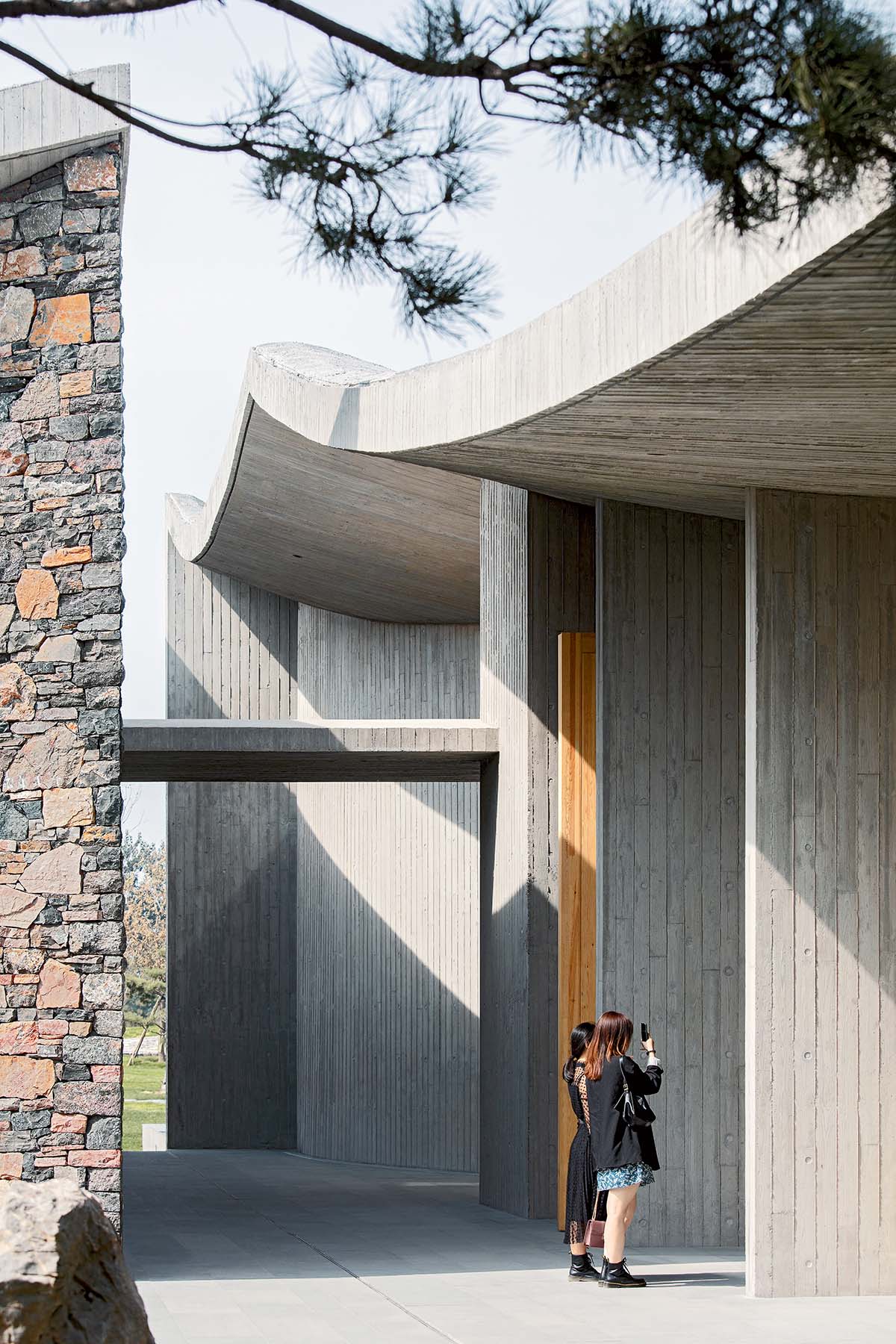 Concrete hyperboloid roofs cover masonry stone art center with a central courtyard in Shandong
