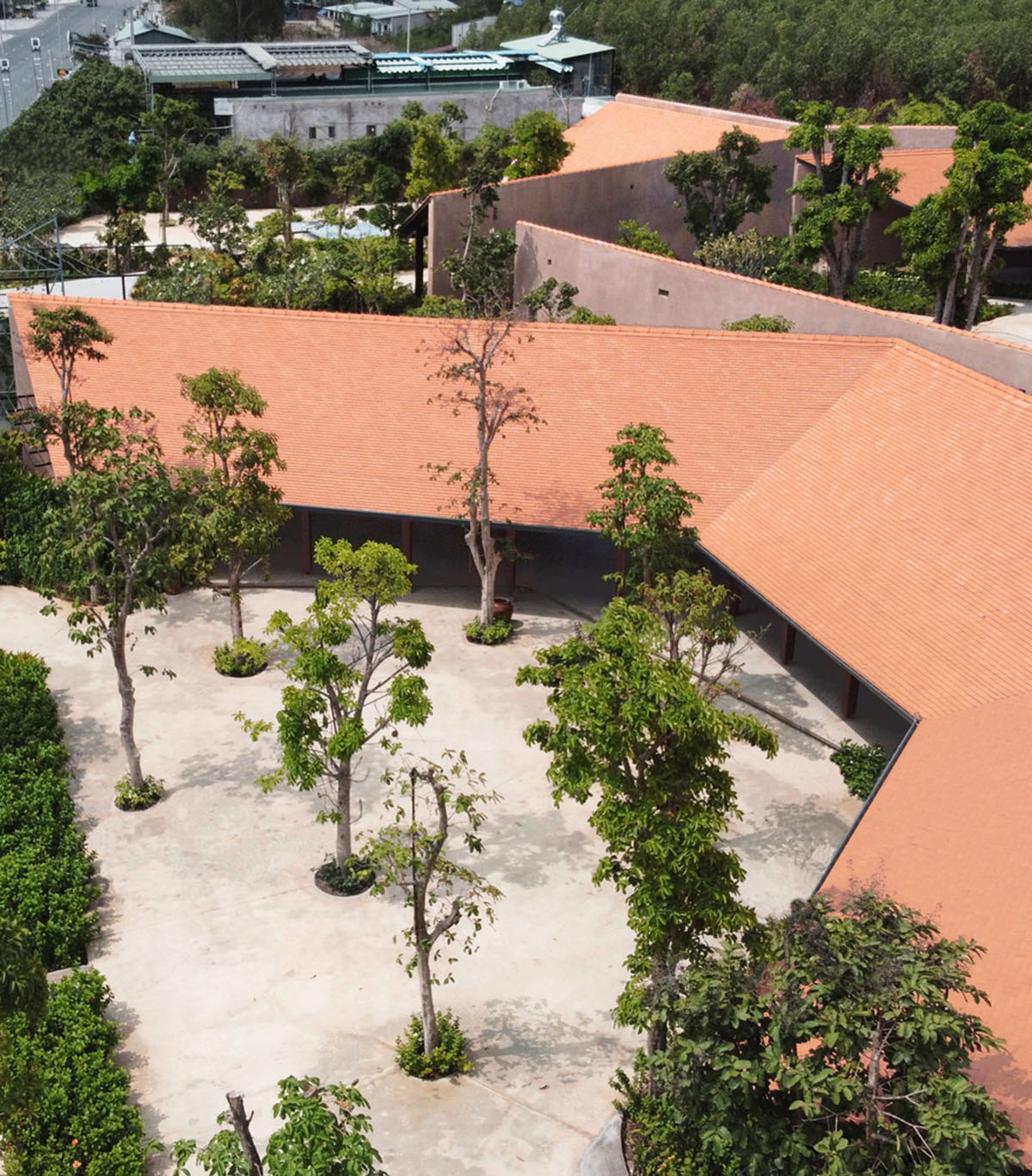 TAA DESIGN built public space with pitched roofs and rough concrete walls painted with pink tones