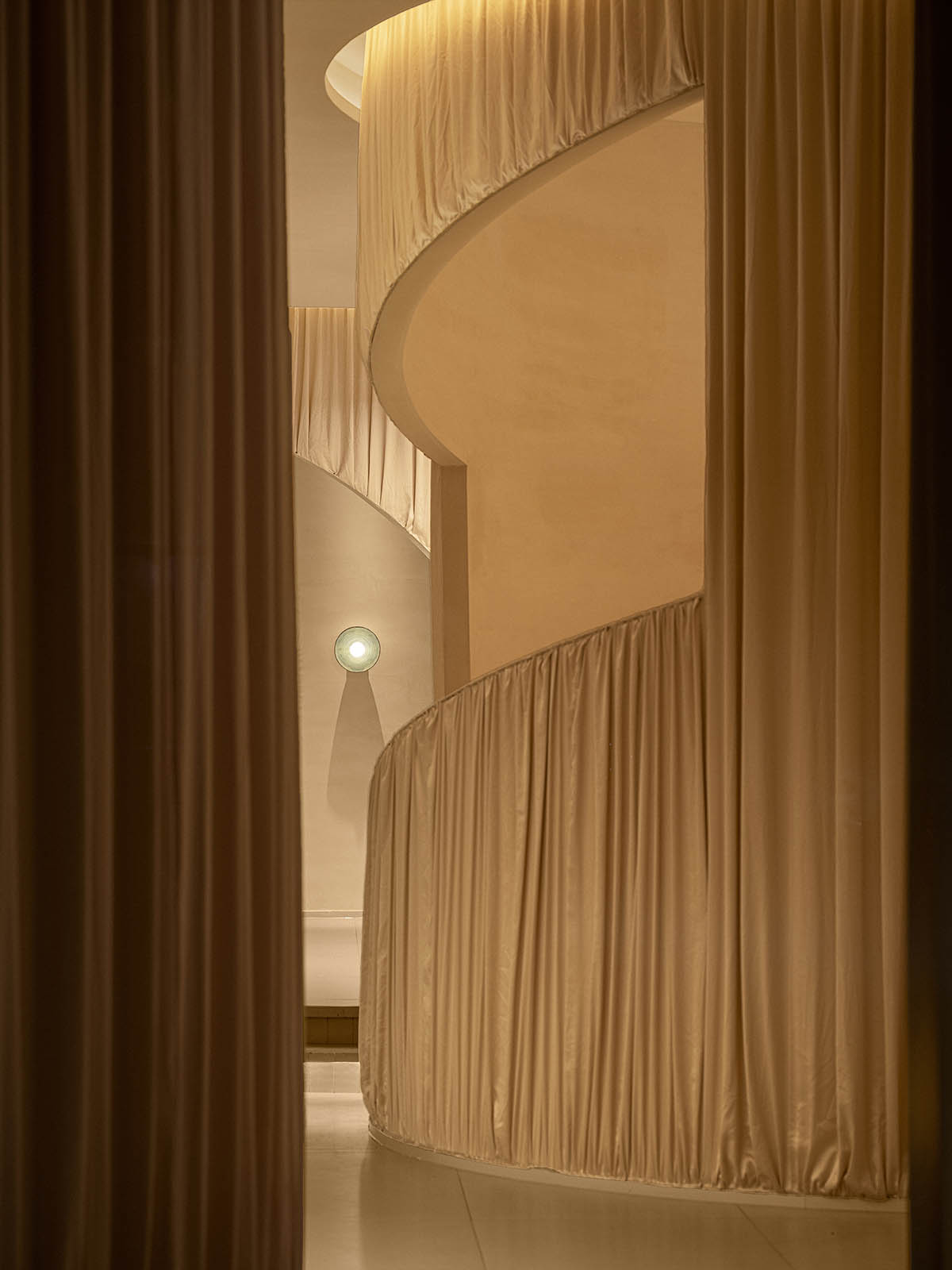 Tea house interiors wrapped by earth-toned fabric curtains act like 