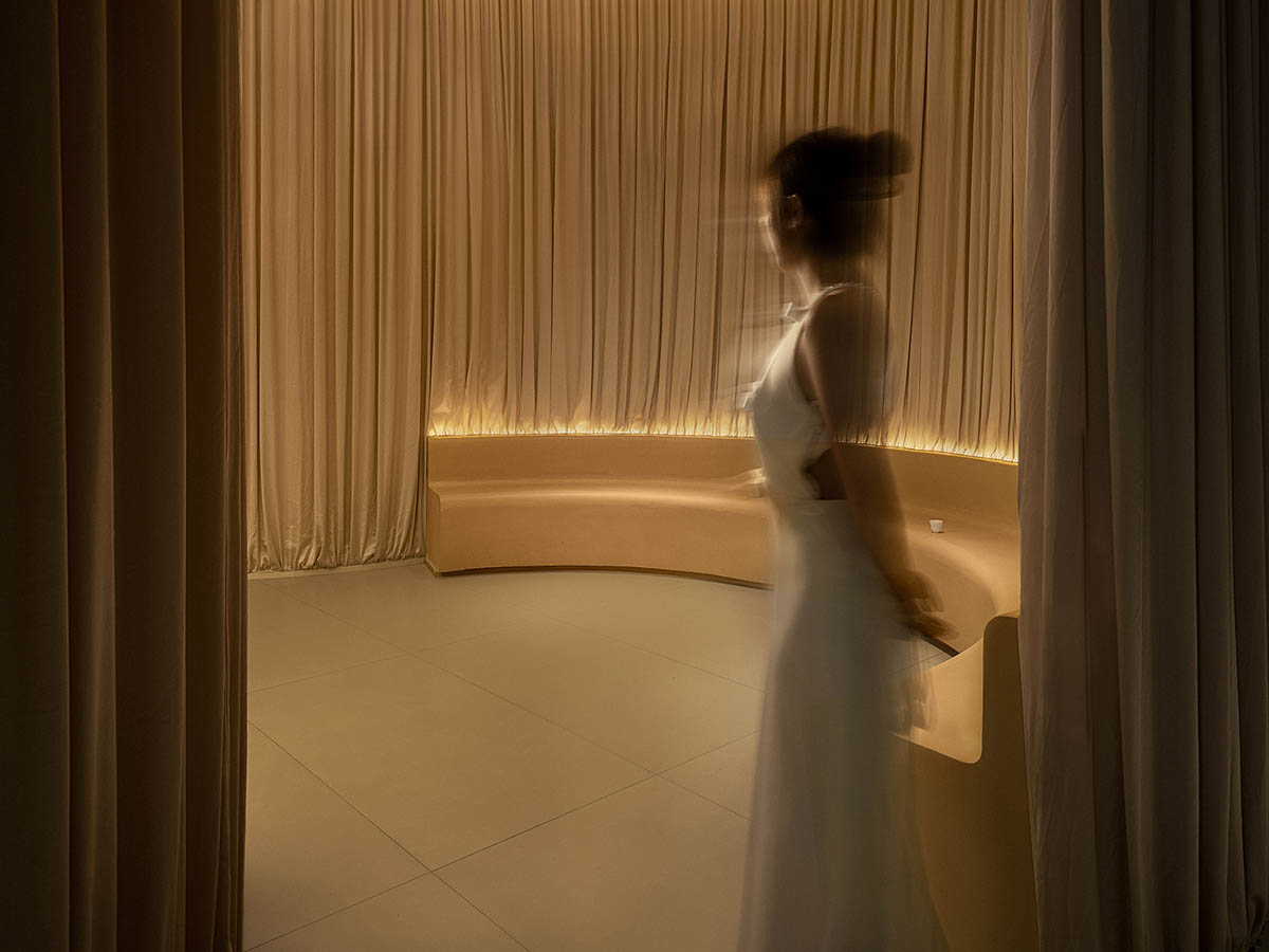 Tea house interiors wrapped by earth-toned fabric curtains act like 