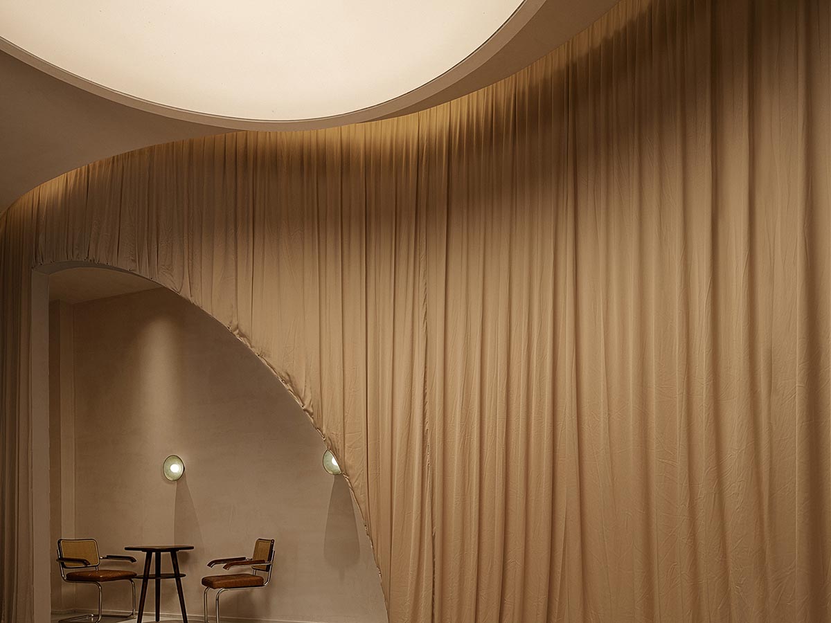 Tea house interiors wrapped by earth-toned fabric curtains act like 