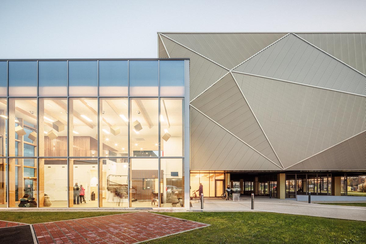 The gold-colored, folded facade gives a striking and symbolic presence to a new sports complex 