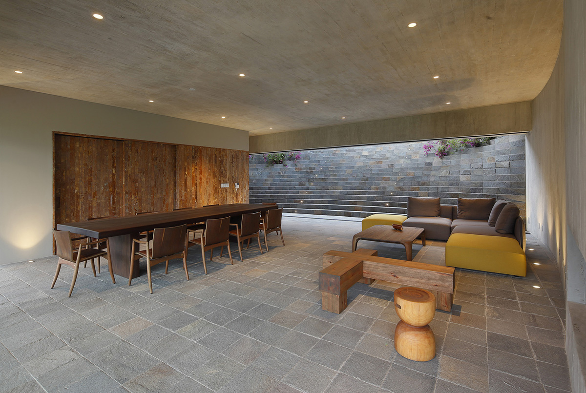 Large semi-buried social space creates a rustic and organic feeling under wooden volume built in Peru
