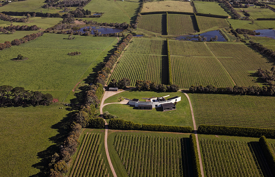 A pair of curved rammed-earth walls hide this holiday home by Wood Marsh on Victorian vineyards