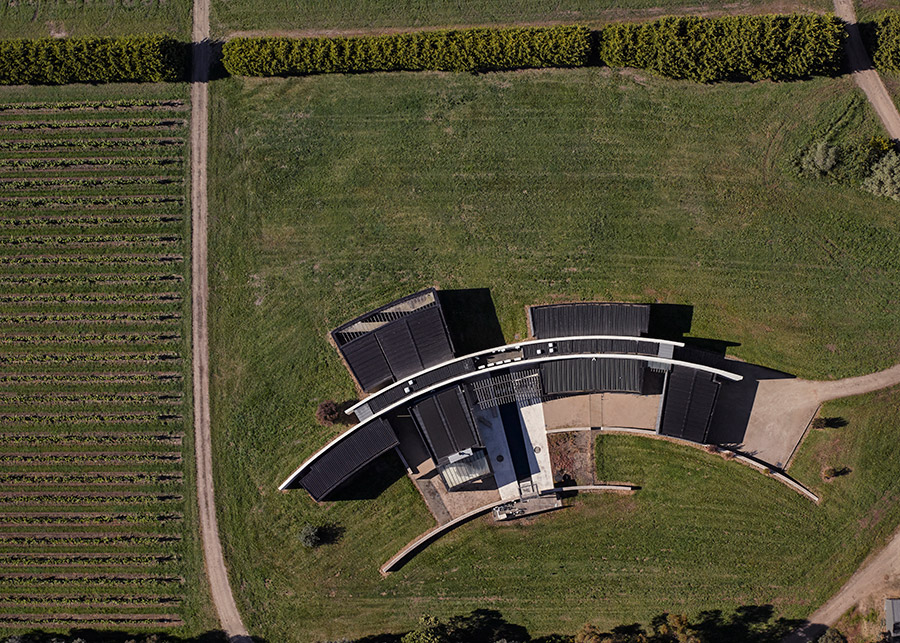 A pair of curved rammed-earth walls hide this holiday home by Wood Marsh on Victorian vineyards