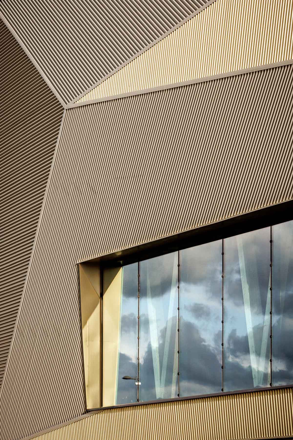 The gold-colored, folded facade gives a striking and symbolic presence to a new sports complex 