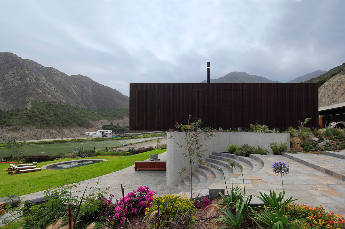 Large semi-buried social space creates a rustic and organic feeling under wooden volume built in Peru