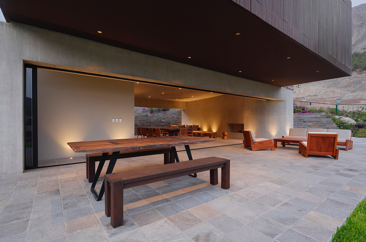 Large semi-buried social space creates a rustic and organic feeling under wooden volume built in Peru