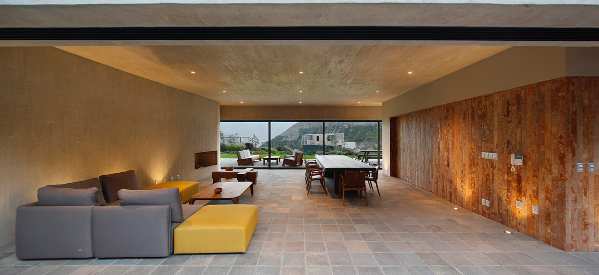 Large semi-buried social space creates a rustic and organic feeling under wooden volume built in Peru