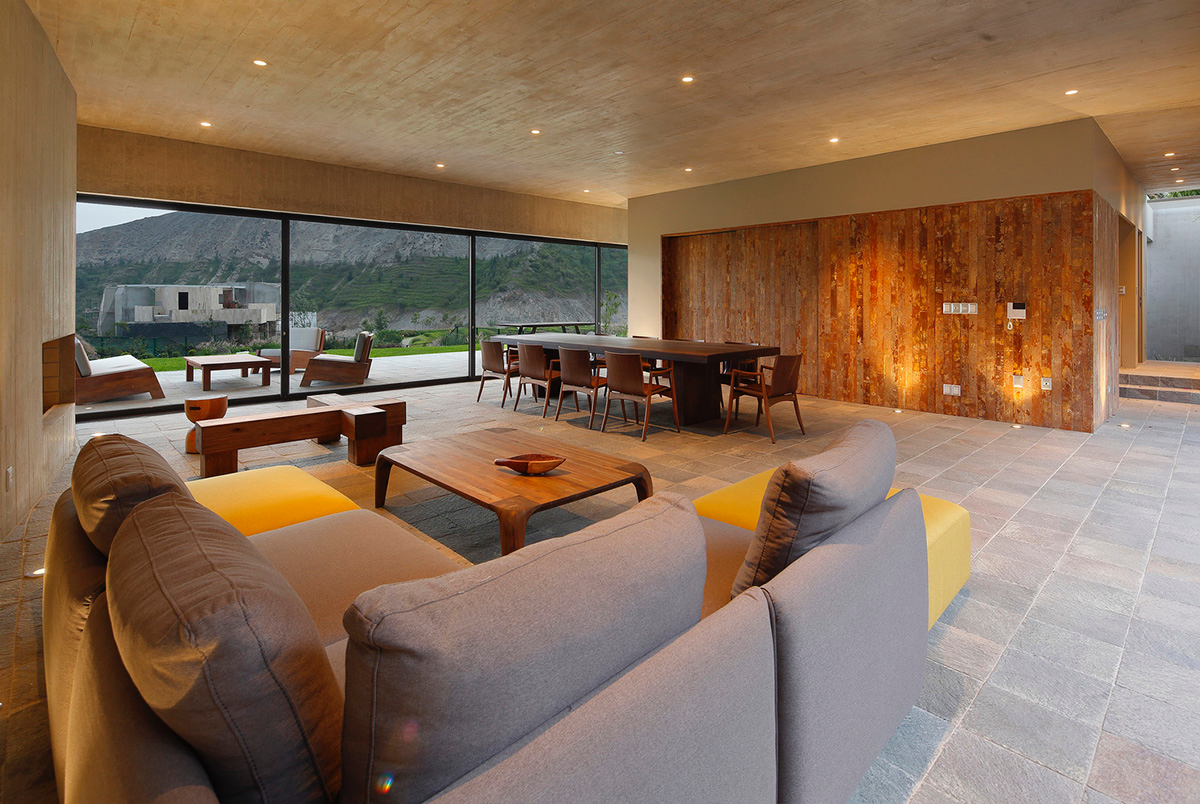 Large semi-buried social space creates a rustic and organic feeling under wooden volume built in Peru