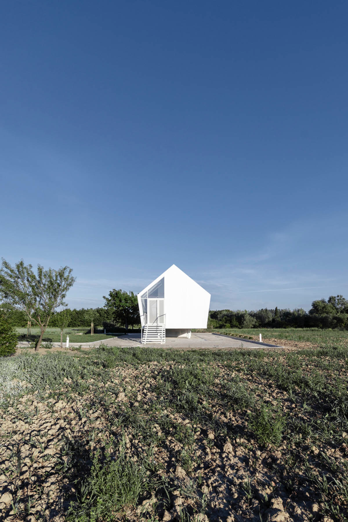 LDA.iMdA architetti associati built modular house raised on stilts in the middle of orchard in Italy