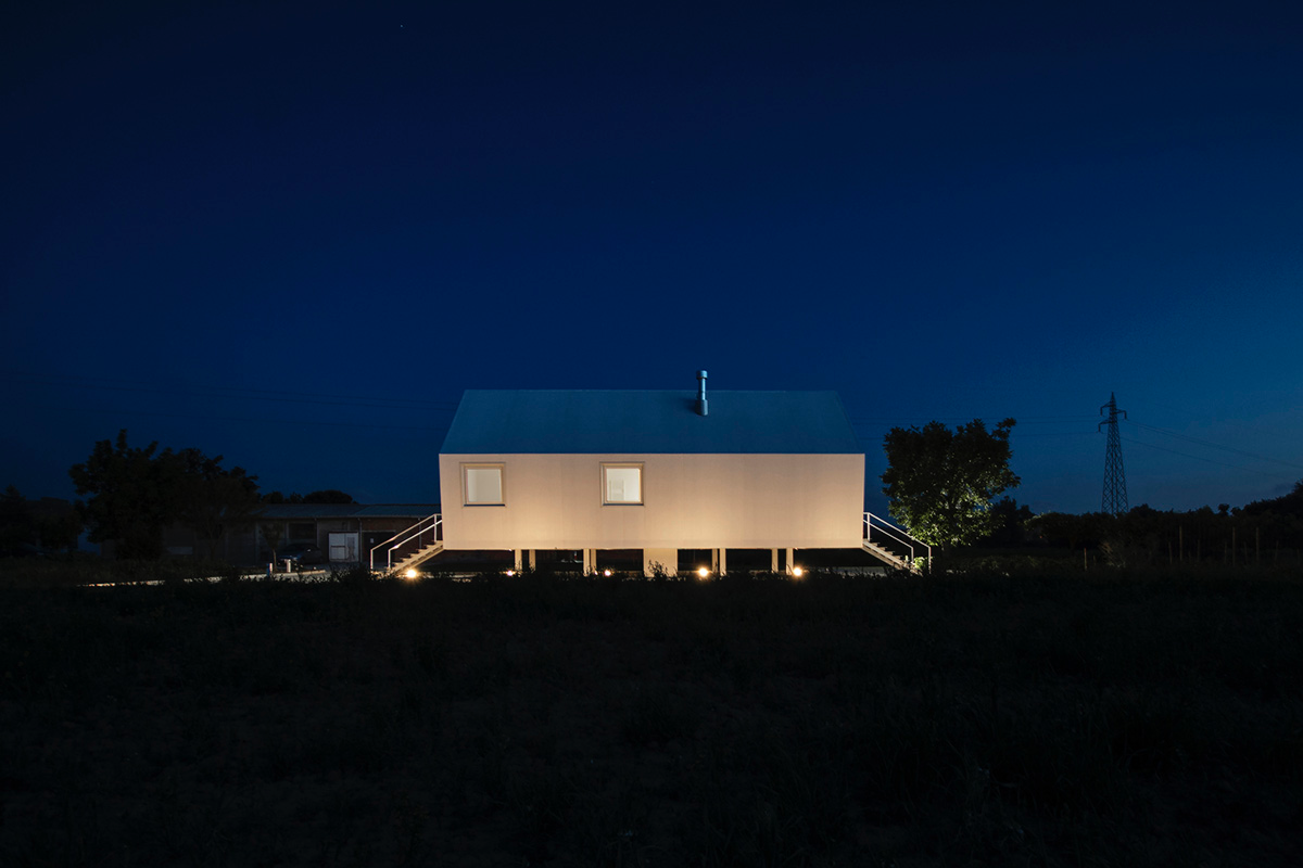 LDA.iMdA architetti associati built modular house raised on stilts in the middle of orchard in Italy