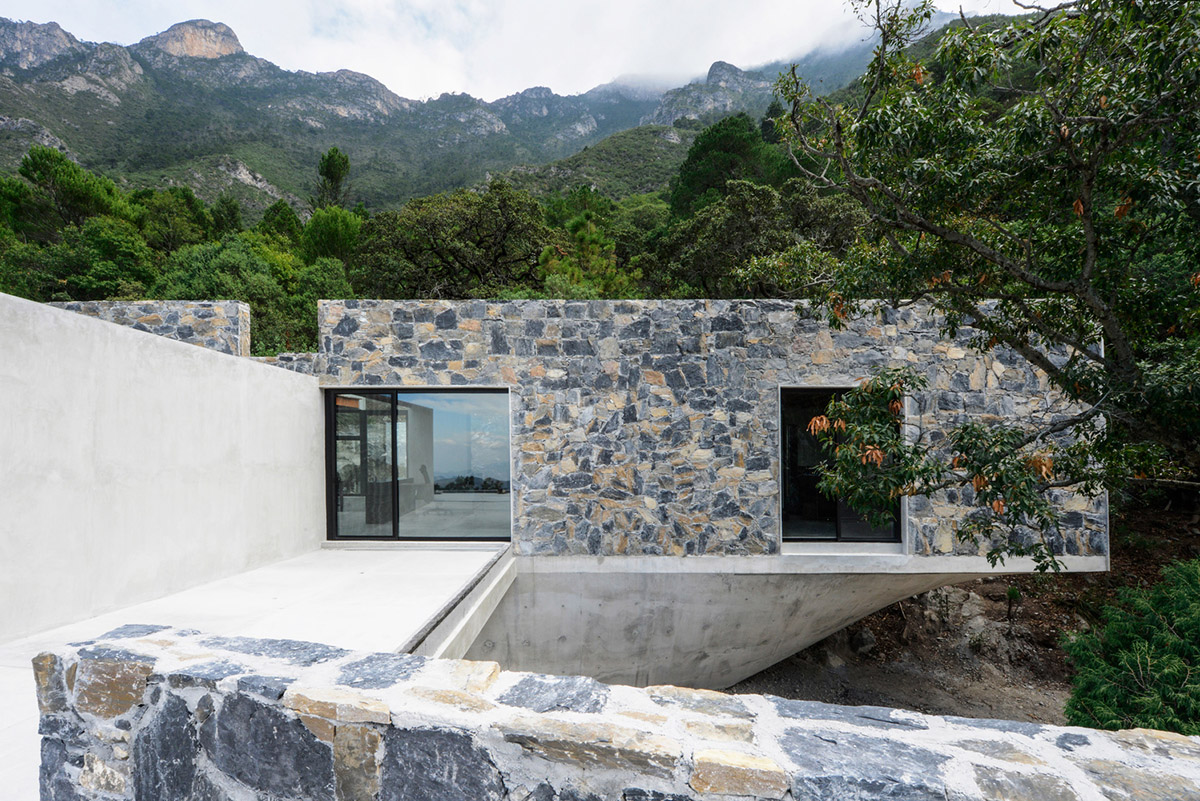 P+0 Arquitectura designs residence mixed with concrete and stone volumes on a complex terrain