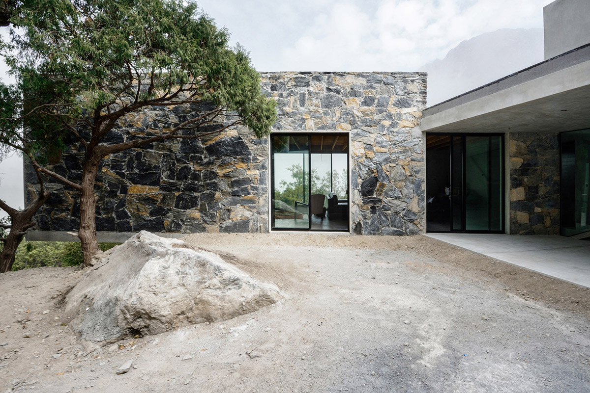 P+0 Arquitectura designs residence mixed with concrete and stone volumes on a complex terrain
