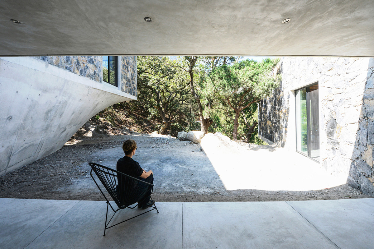 P+0 Arquitectura designs residence mixed with concrete and stone volumes on a complex terrain